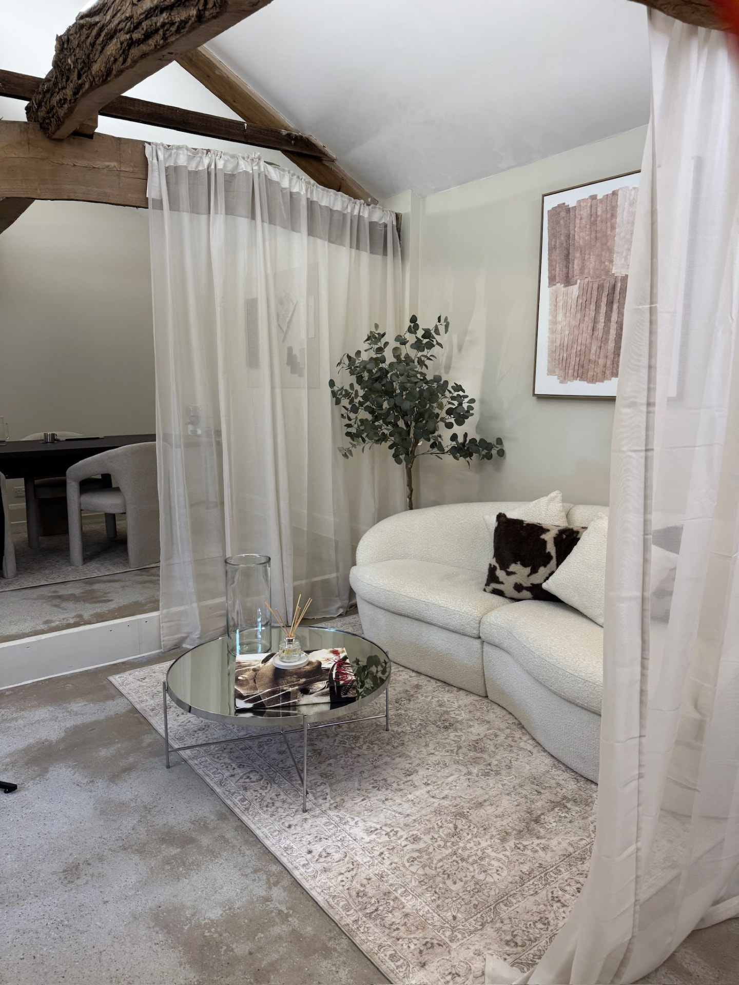 The bouclé sofa with a cowhide cushion on a Persian-style rug in the Mondays living area